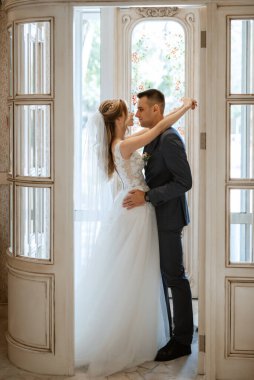 Gelin ve damat bir kokteyl barının içinde. Parlak bir atmosferde, bir bardak içkiyle.