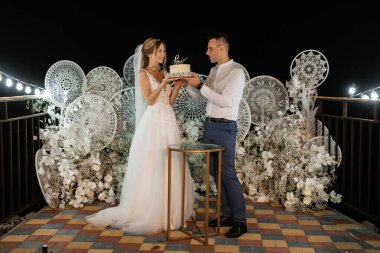 newlyweds happily cut, laugh and taste the wedding cake