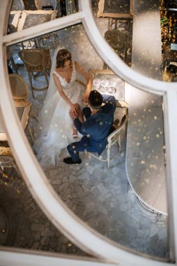 Gelin ve damat bir kokteyl barının içinde. Parlak bir atmosferde, bir bardak içkiyle.