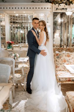 Gelin ve damat bir kokteyl barının içinde. Parlak bir atmosferde, bir bardak içkiyle.