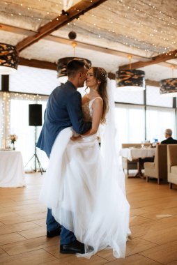 Gelin ve damadın ilk düğün dansı gün batımında restoranın içinde.