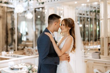 Gelin ve damat bir kokteyl barının içinde. Parlak bir atmosferde, bir bardak içkiyle.