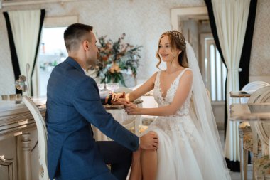 Gelin ve damat bir kokteyl barının içinde. Parlak bir atmosferde, bir bardak içkiyle.