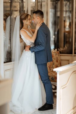 Gelin ve damat bir kokteyl barının içinde. Parlak bir atmosferde, bir bardak içkiyle.