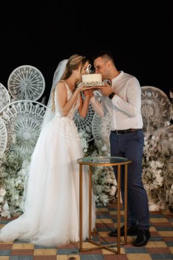 newlyweds happily cut, laugh and taste the wedding cake
