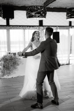 Gelin ve damadın ilk düğün dansı gün batımında restoranın içinde.