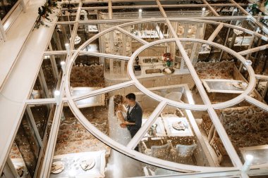 Gelin ve damat bir kokteyl barının içinde. Parlak bir atmosferde, bir bardak içkiyle.