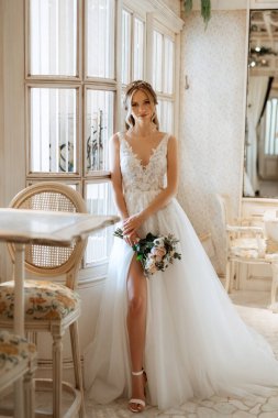 Parlak bir kafede aynalı beyaz elbiseli bir gelinin portresi.