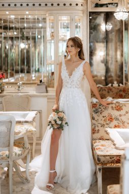 Parlak bir kafede aynalı beyaz elbiseli bir gelinin portresi.