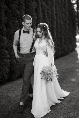 Yazın kozalaklı bir parkta gelin ve damadın düğün yürüyüşü.