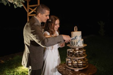 newlyweds happily cut, laugh and taste the wedding cake