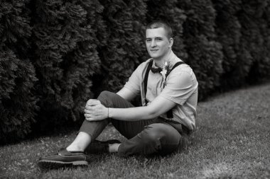 Genç adam, yeşil thuja arka planında boho tarzında damat.