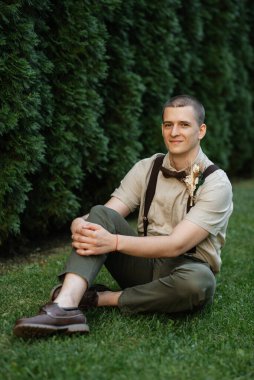 Genç adam, yeşil thuja arka planında boho tarzında damat.