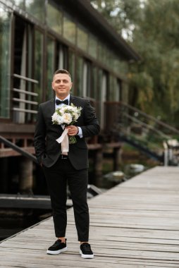 the first meeting of the bride and groom in wedding dresses on the pier near the water