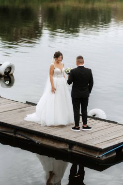 the first meeting of the bride and groom in wedding dresses on the pier near the water