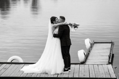 the first meeting of the bride and groom in wedding dresses on the pier near the water