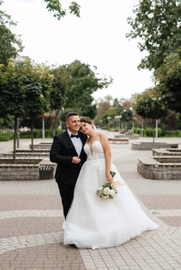 the groom in a brown suit and the bride in a white dress in an urban atmosphere