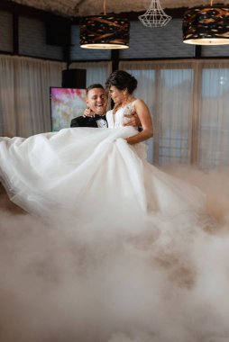 the first dance of the bride and groom inside a restaurant with heavy smoke