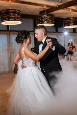 the first dance of the bride and groom inside a restaurant with heavy smoke