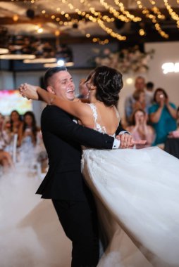 the first dance of the bride and groom inside a restaurant with heavy smoke