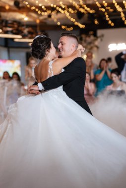 the first dance of the bride and groom inside a restaurant with heavy smoke