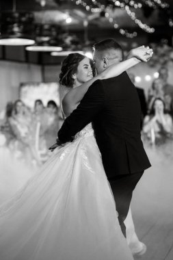 the first dance of the bride and groom inside a restaurant with heavy smoke