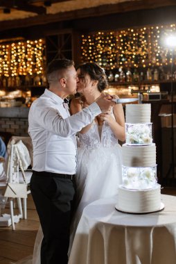 newlyweds happily cut, laugh and taste the wedding cake