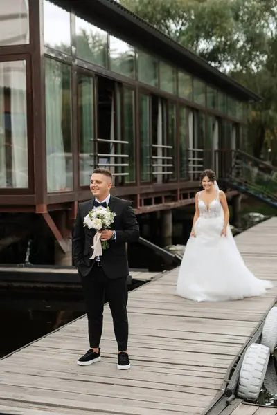 the first meeting of the bride and groom in wedding dresses on the pier near the water