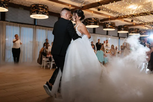 the first dance of the bride and groom inside a restaurant with heavy smoke