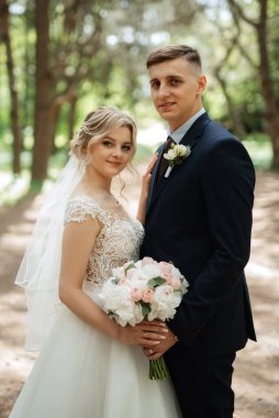 the groom and the bride are walking in the forest on a bright day