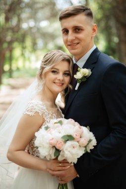 the groom and the bride are walking in the forest on a bright day