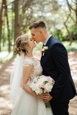the groom and the bride are walking in the forest on a bright day