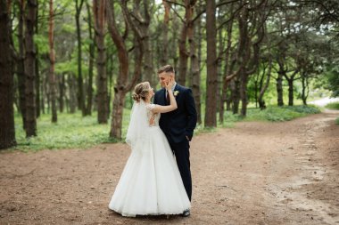 the groom and the bride are walking in the forest on a bright day