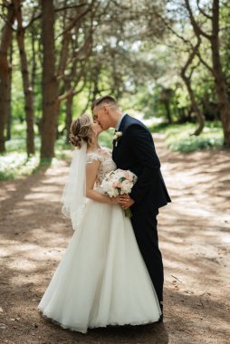 the groom and the bride are walking in the forest on a bright day