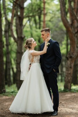 the groom and the bride are walking in the forest on a bright day