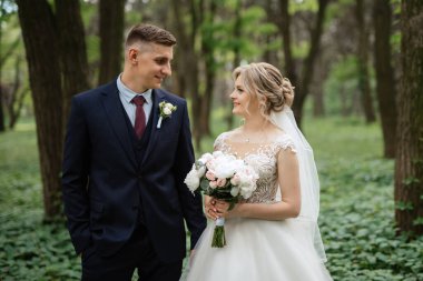 the groom and the bride are walking in the forest on a bright day