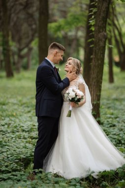 the groom and the bride are walking in the forest on a bright day