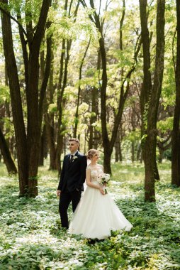 Damat ve gelin aydınlık bir günde ormanda yürüyorlar.