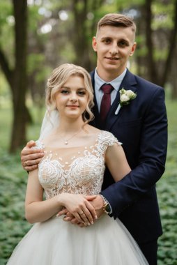 the groom and the bride are walking in the forest on a bright day