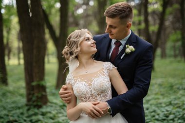 the groom and the bride are walking in the forest on a bright day