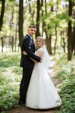 the groom and the bride are walking in the forest on a bright day