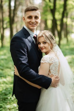 the groom and the bride are walking in the forest on a bright day