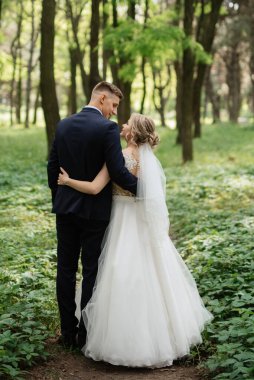 the groom and the bride are walking in the forest on a bright day