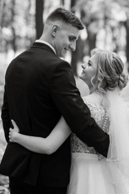 the groom and the bride are walking in the forest on a bright day
