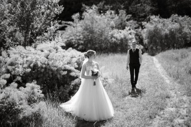 the groom and the bride are walking in the forest on a bright day