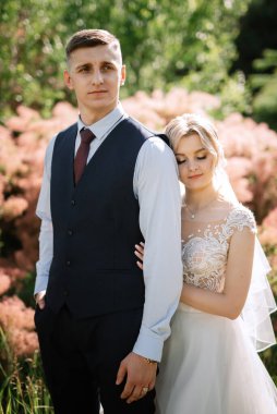 the groom and the bride are walking in the forest on a bright day
