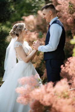 the groom and the bride are walking in the forest on a bright day