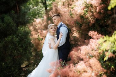 the groom and the bride are walking in the forest on a bright day