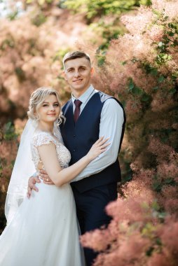 the groom and the bride are walking in the forest on a bright day