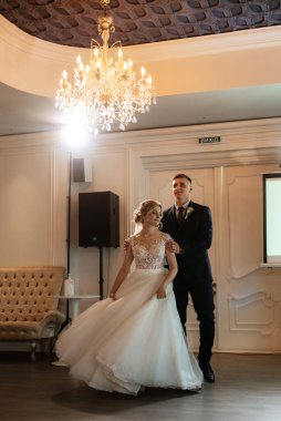 Gelin ve damadın ilk düğün dansı gün batımında restoranın içinde.